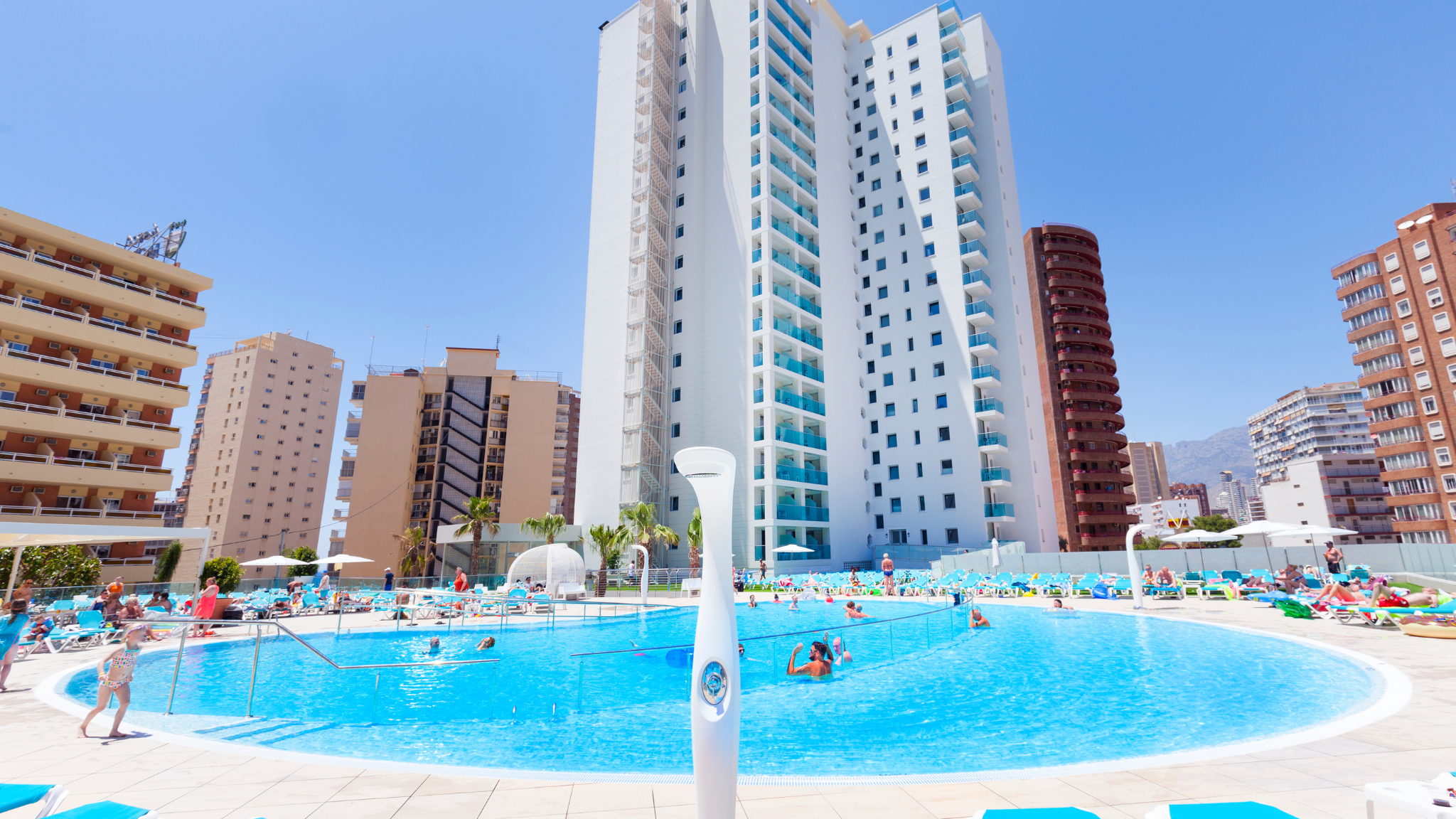 people are swimming in a large pool in front of a tall building