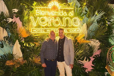 two men pose in front of a sign that says bienvenido al verano - 