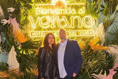 a man and woman pose in front of a sign that says bienvenido al verano - 