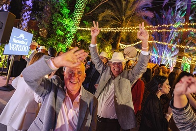 un grupo de personas bailan en una fiesta con un cartel que dice bienvenida al verano - 