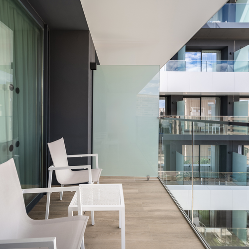 un balcón con sillas blancas y una mesa blanca