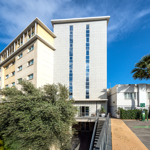 un gran edificio blanco y amarillo con palmeras alrededor