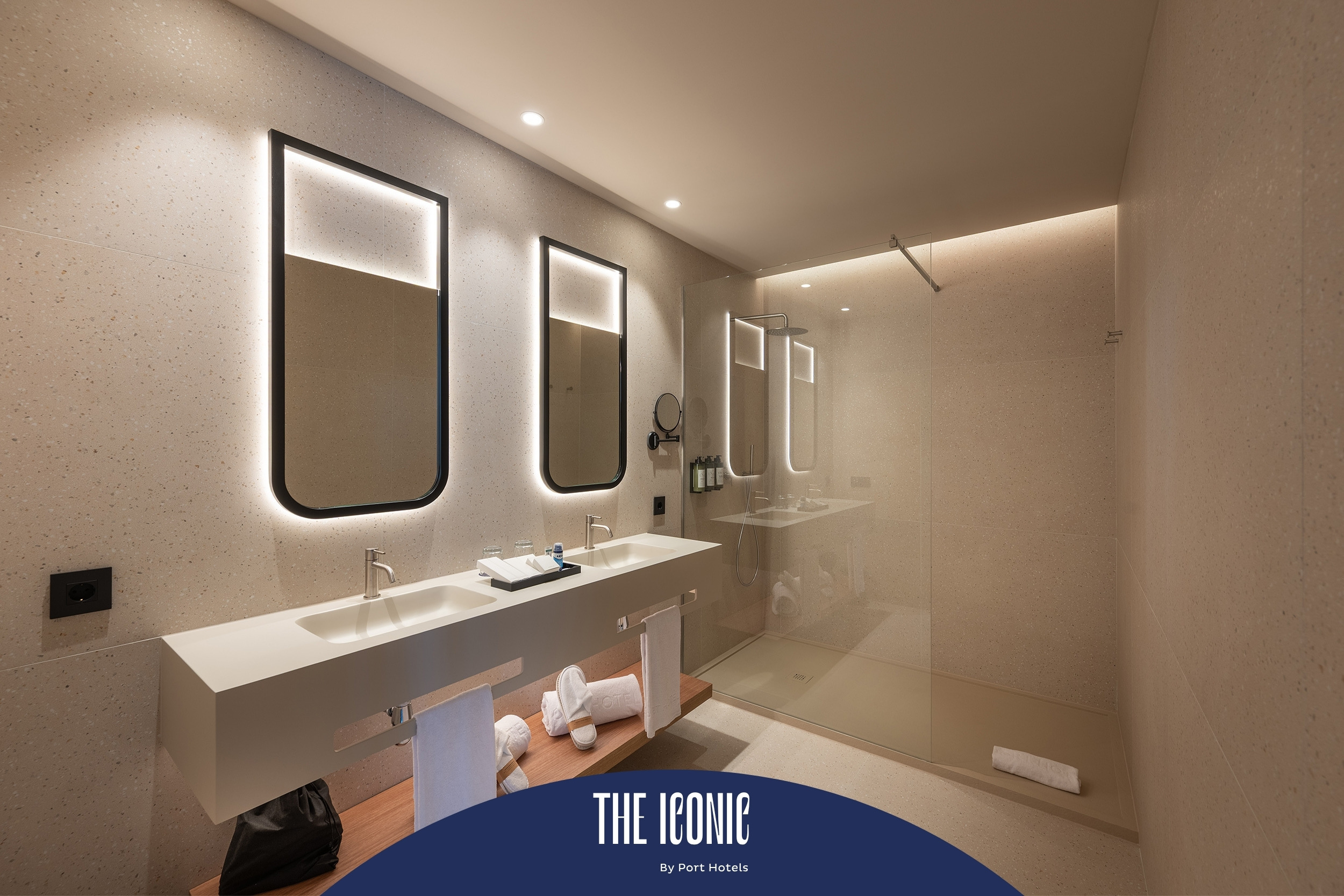 Modern hotel bathroom with double sinks and walk-in shower. Port Hotels: Corporativa