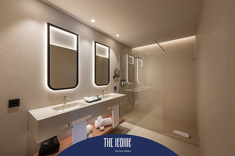 Modern hotel bathroom with double sinks and walk-in shower. Port Hotels: Corporativa