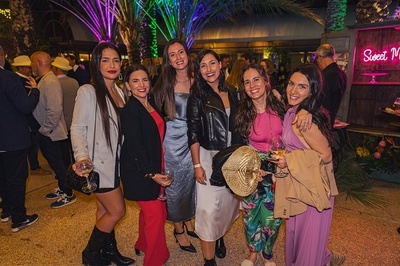 a group of women pose in front of a neon sign that says sweet - 