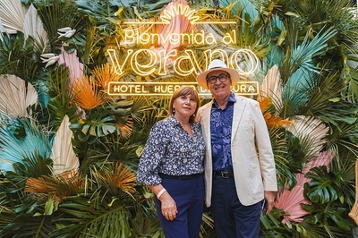 a man and woman standing in front of a sign that says bienvenido al verano - 