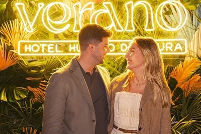 a man and woman are standing in front of a neon sign that says verano - 