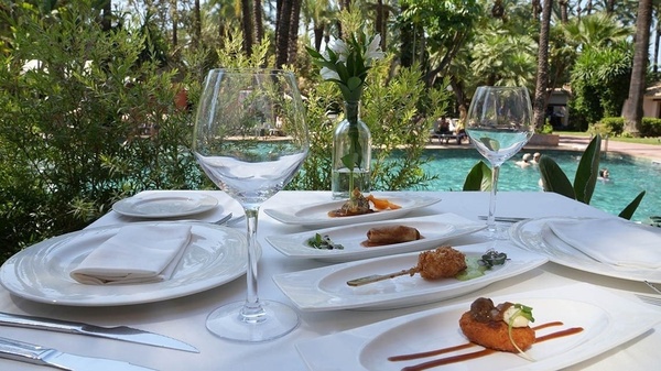 a table with plates of food and wine glasses in front of a pool