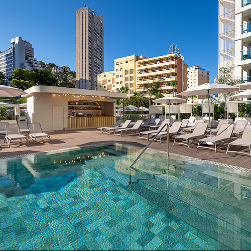 Port Hotels: Corporativa: Piscina con tumbonas y bar en hotel moderno, vista a edificios urbanos.