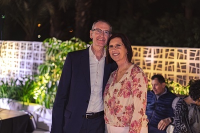 a man in a suit and a woman in a floral shirt pose for a photo - 
