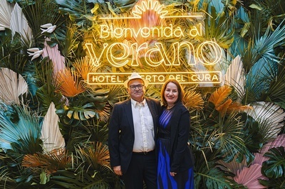 a man and woman standing in front of a sign that says bienvenido al verano - 