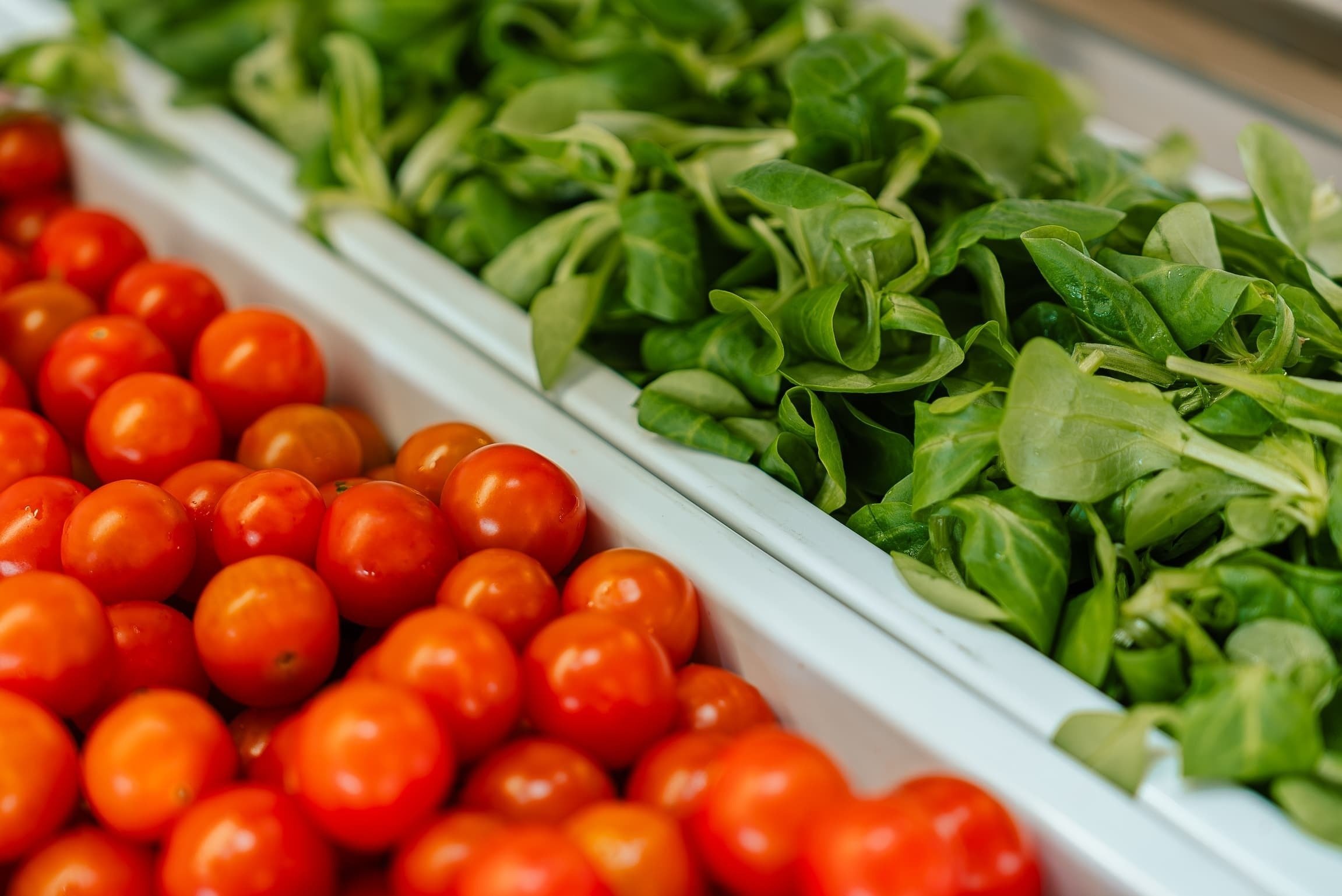 a tray of tomatoes next to a tray of spinach