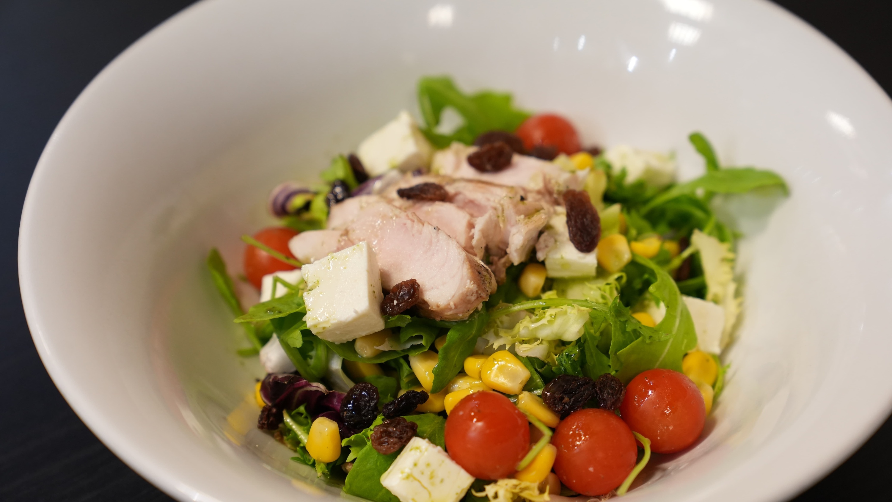 a white bowl filled with a salad with tomatoes corn and cheese