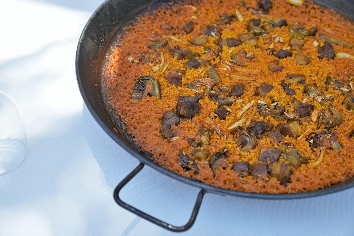 a pan of rice with meat and artichokes in it