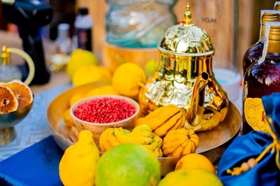una tetera dorada está rodeada de limones y granos de pimienta rosa - 