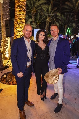 a man in a blue suit stands next to a woman and a man in a white shirt - 