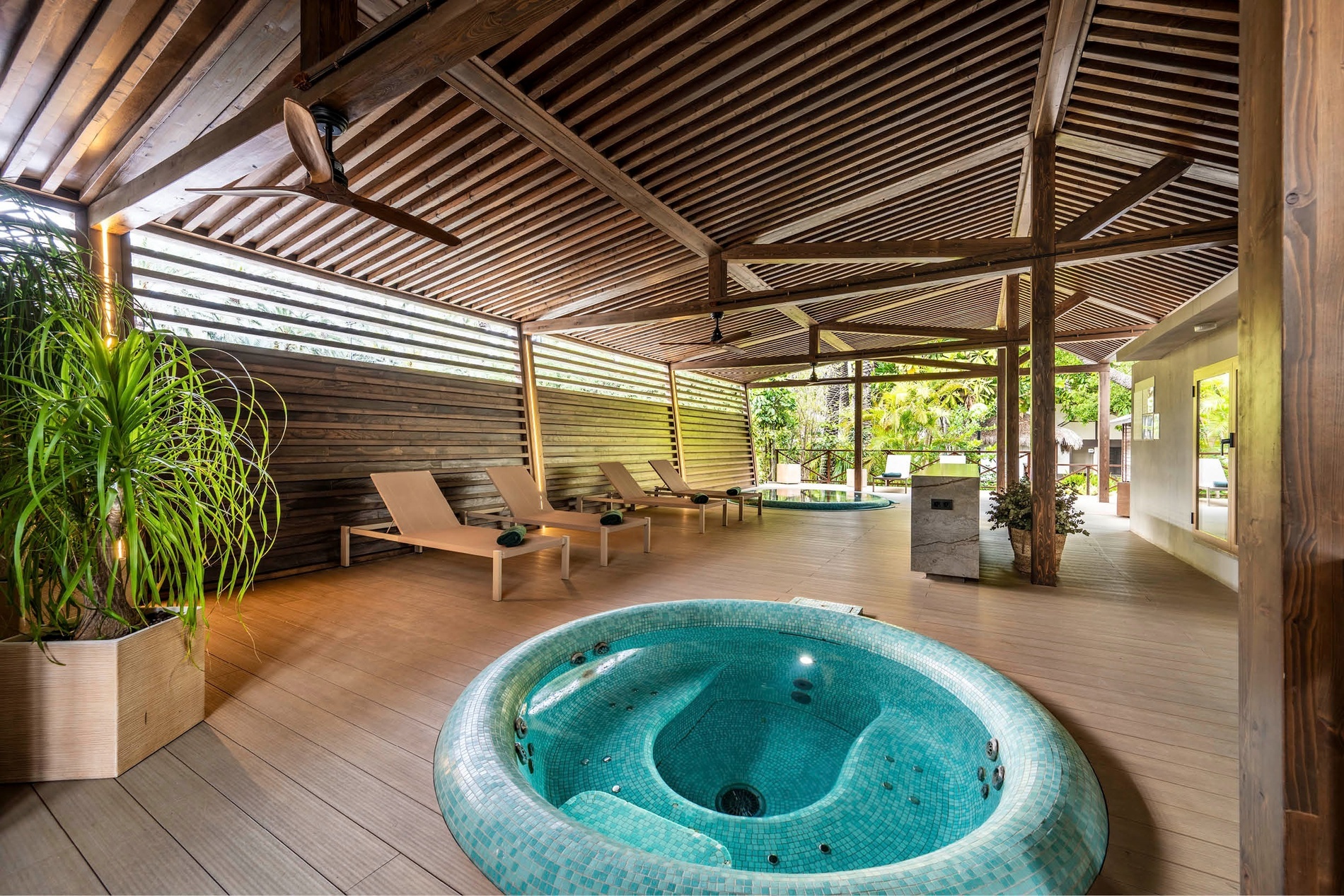 a hot tub is surrounded by lounge chairs under a wooden roof
