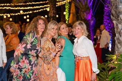 un grupo de mujeres posando para una foto y una de ellas sostiene una copa de vino - 