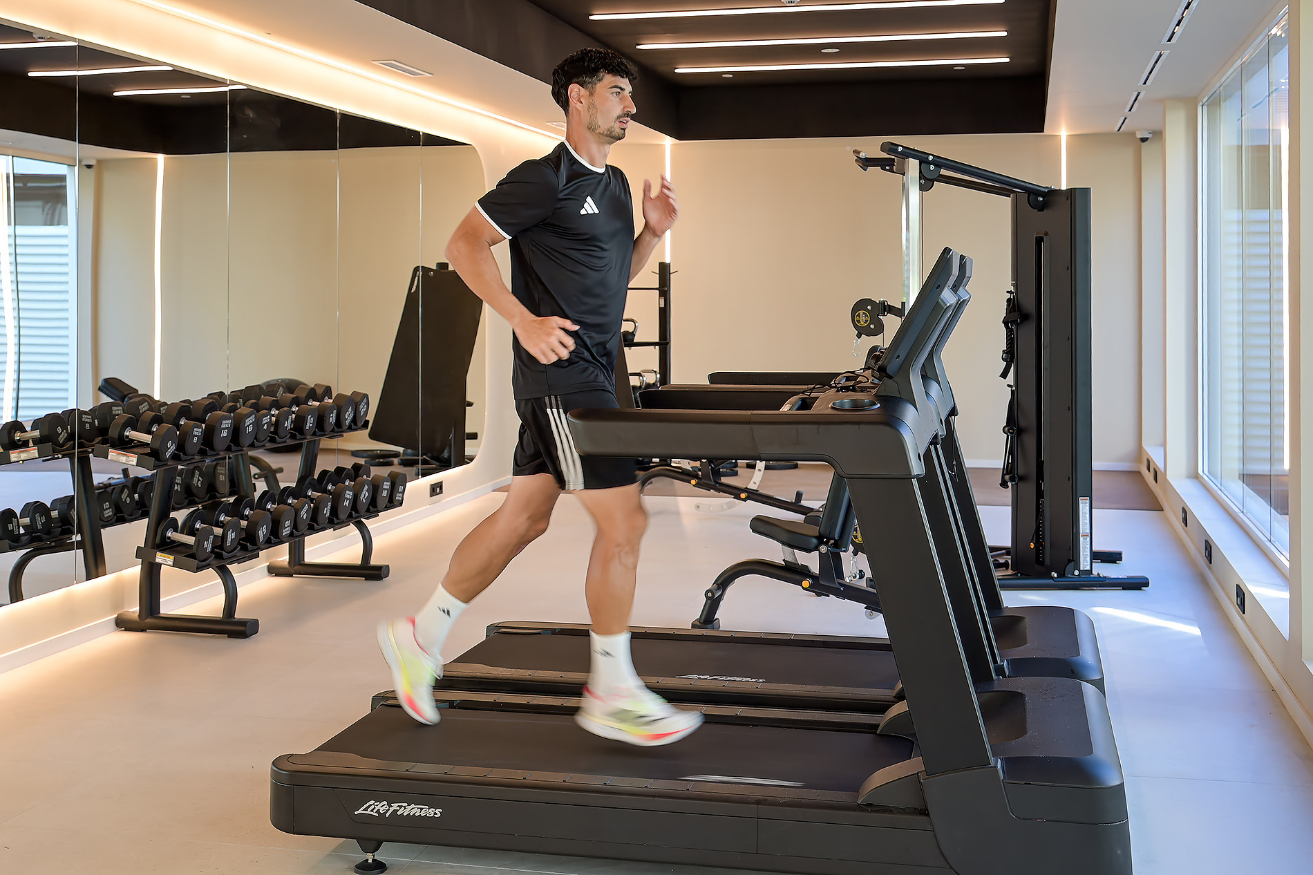 Un hombre corre en una cinta de correr en el gimnasio del hotel. Bienestar Port Benidorm Hotel & Spa | Port Hotels | Web Oficial