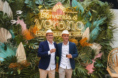 two men standing in front of a sign that says bienvenido al verano - 