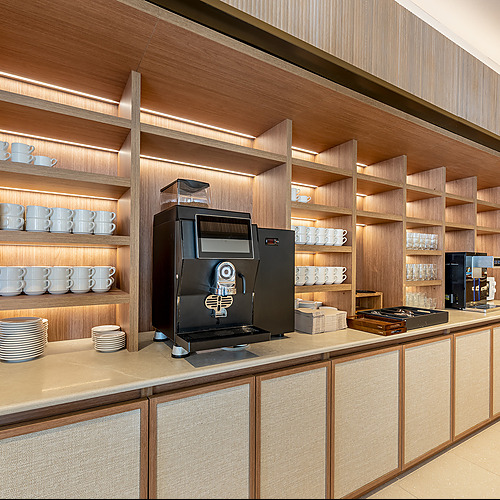 Estación de café y bebidas para huéspedes. Port Hotels: Corporativa en hotel moderno con diseño en madera.