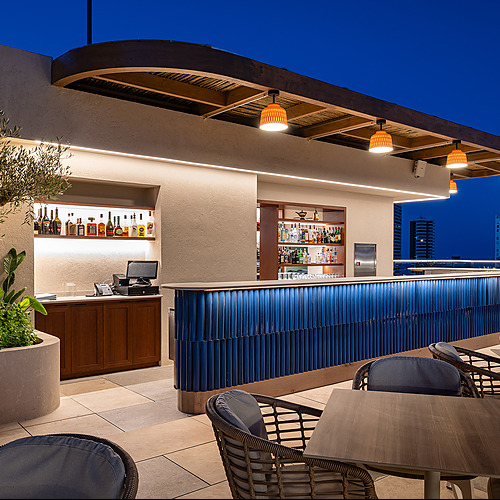 Bar en terraza de hotel con vista nocturna Port Hotels: Corporativa. Mobiliario moderno y luces cálidas.