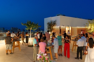 a group of people are gathered on a rooftop at night - 