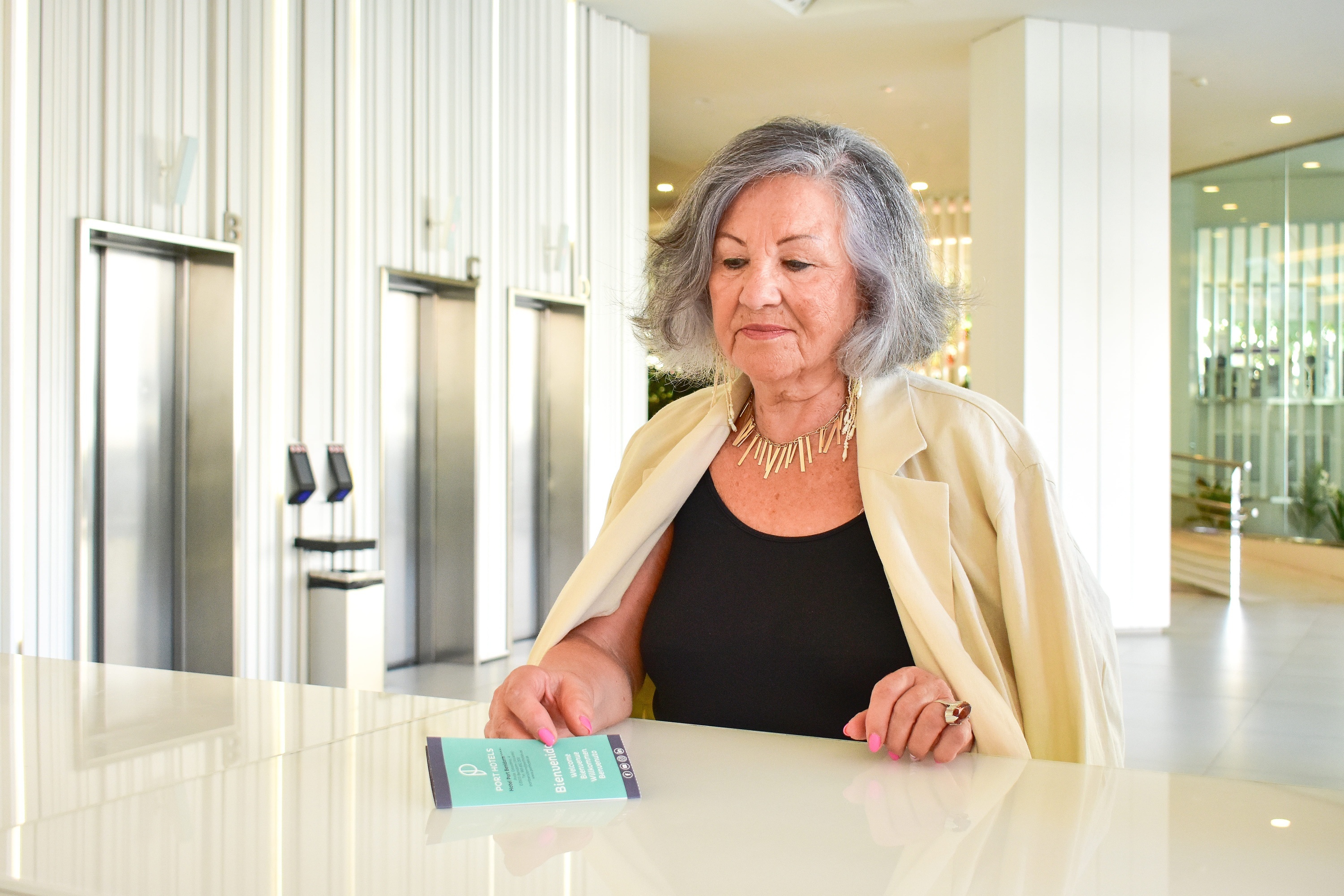 an older woman stands at a counter holding a ticket that says ' tickets ' on it