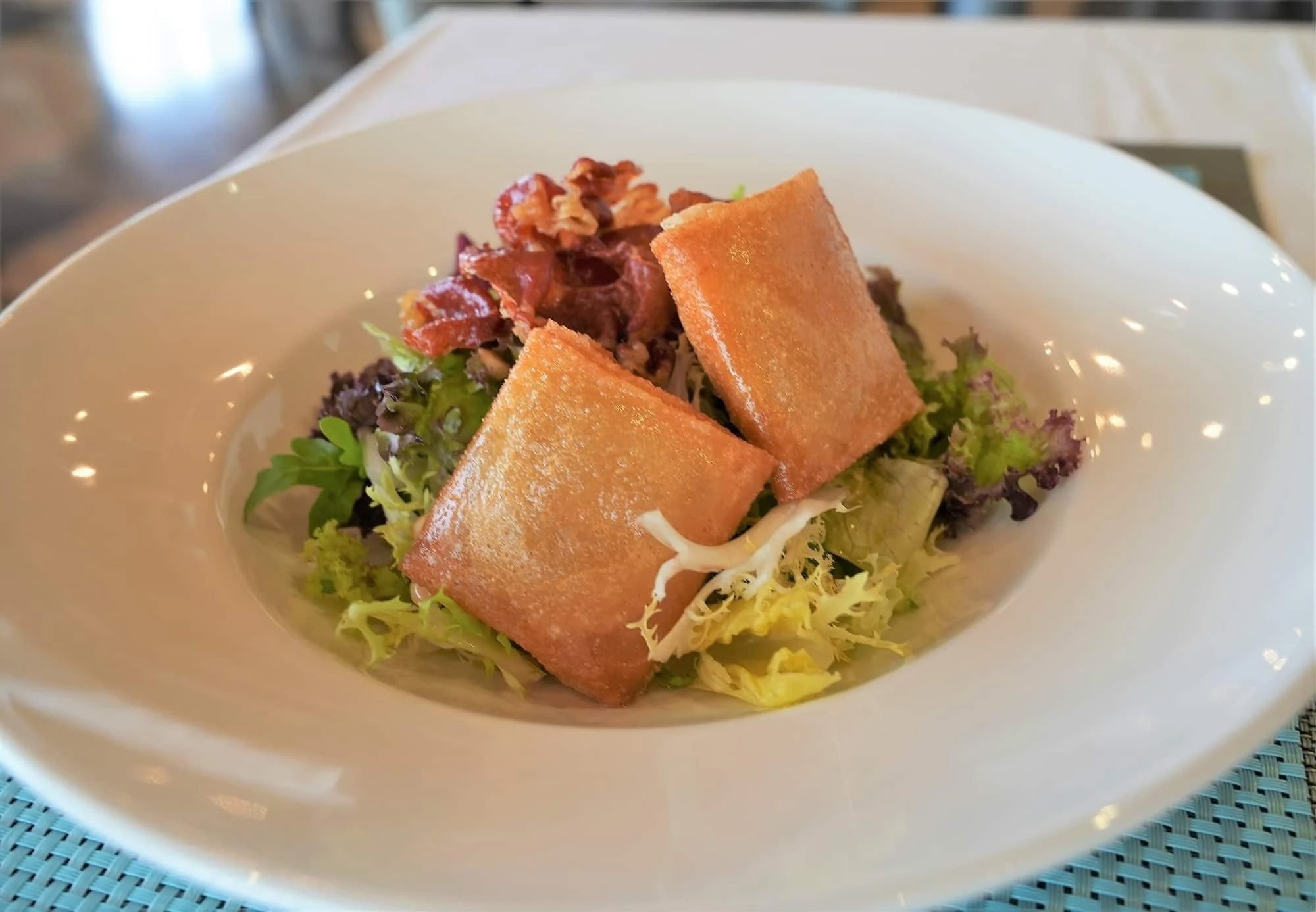 un plato blanco con una ensalada y un trozo de pollo frito