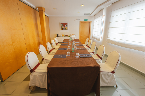 una sala de conferencias con mesas y sillas y una pantalla