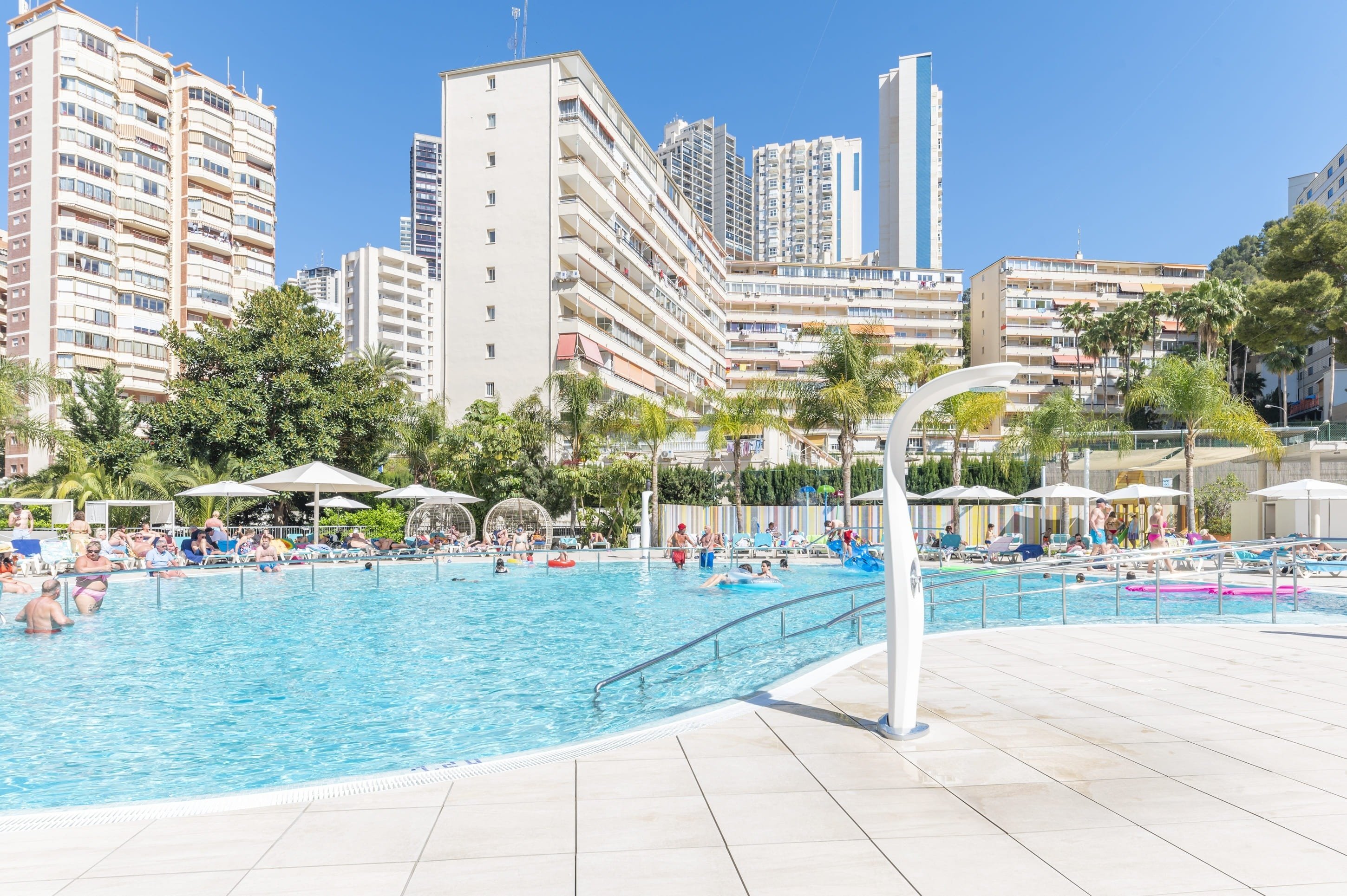 a large swimming pool surrounded by palm trees and buildings