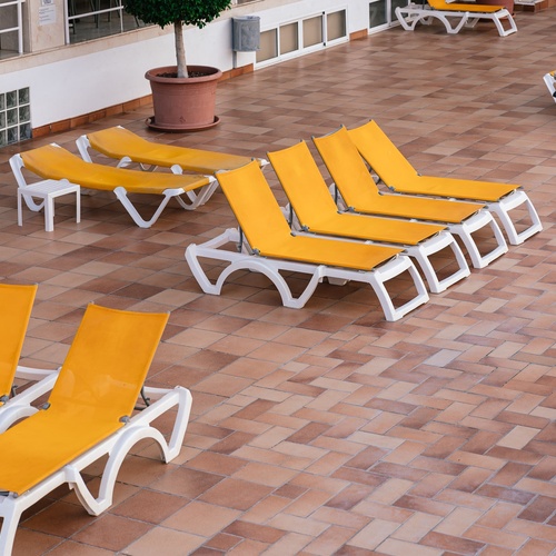 a row of yellow lounge chairs are lined up on a tiled floor