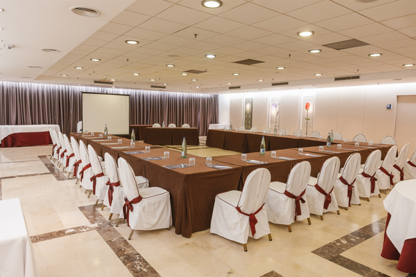 una sala de conferencias con mesas y sillas y una pantalla