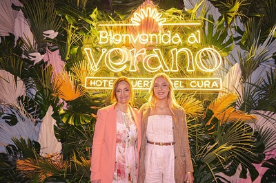 two women stand in front of a sign that says bienvenido al verano - 