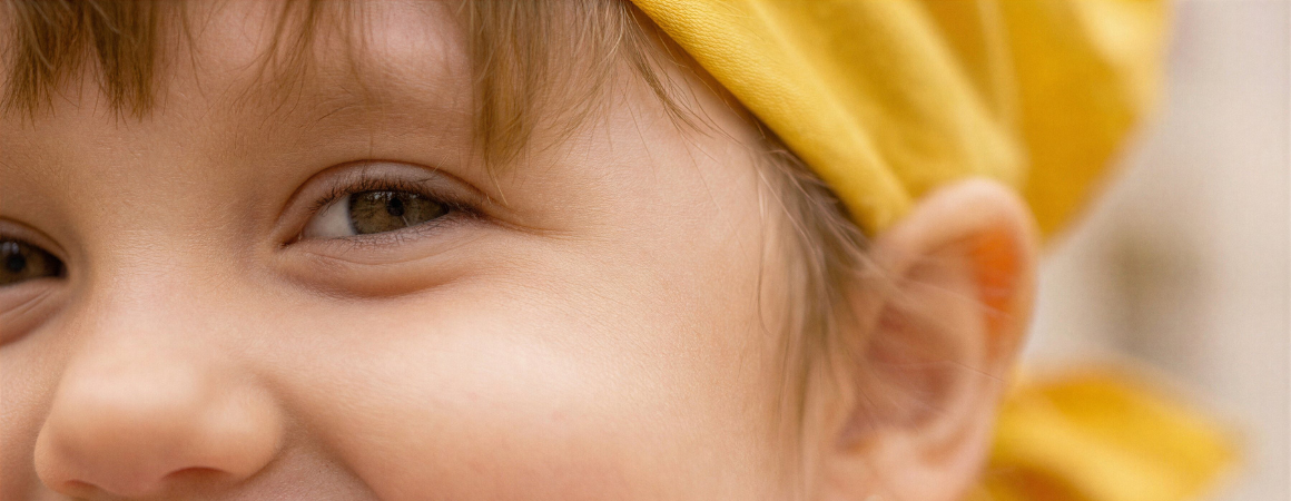  a little girl wearing a pink shirt and a yellow cape is flexing her muscles