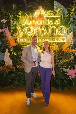 a man and woman pose in front of a sign that says bienvenido al verano - 