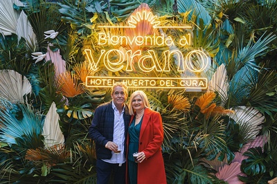 a man and woman standing in front of a sign that says hotel huerto del cura - 
