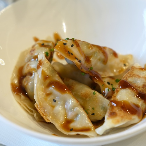 a white bowl filled with fried dumplings and sauce