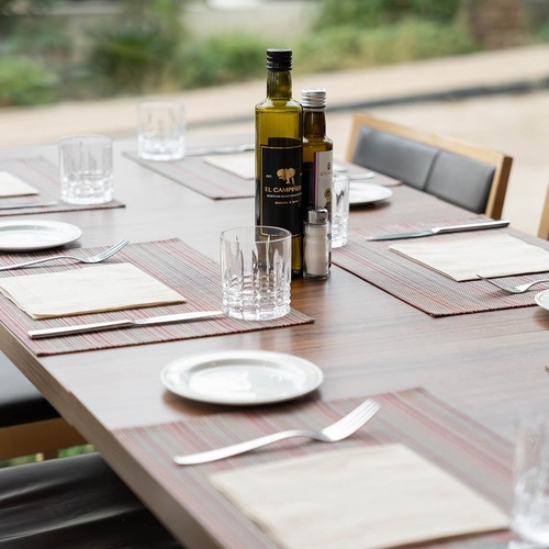 una mesa con platos y cubiertos y una botella de aceite de oliva