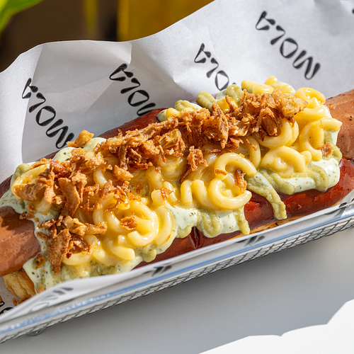 un perrito caliente con macaroni y queso en una bandeja