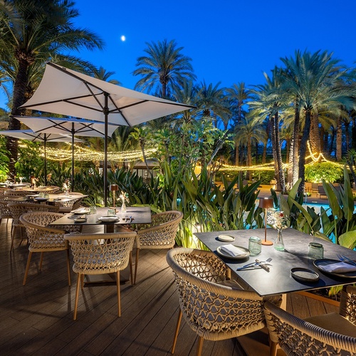 a patio with tables and chairs and umbrellas at night