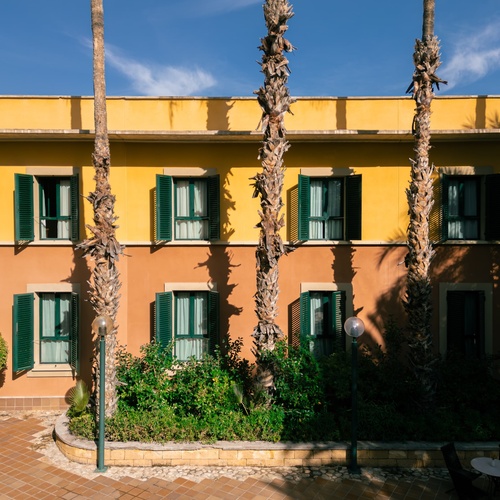 un edificio amarillo con persianas verdes y palmeras