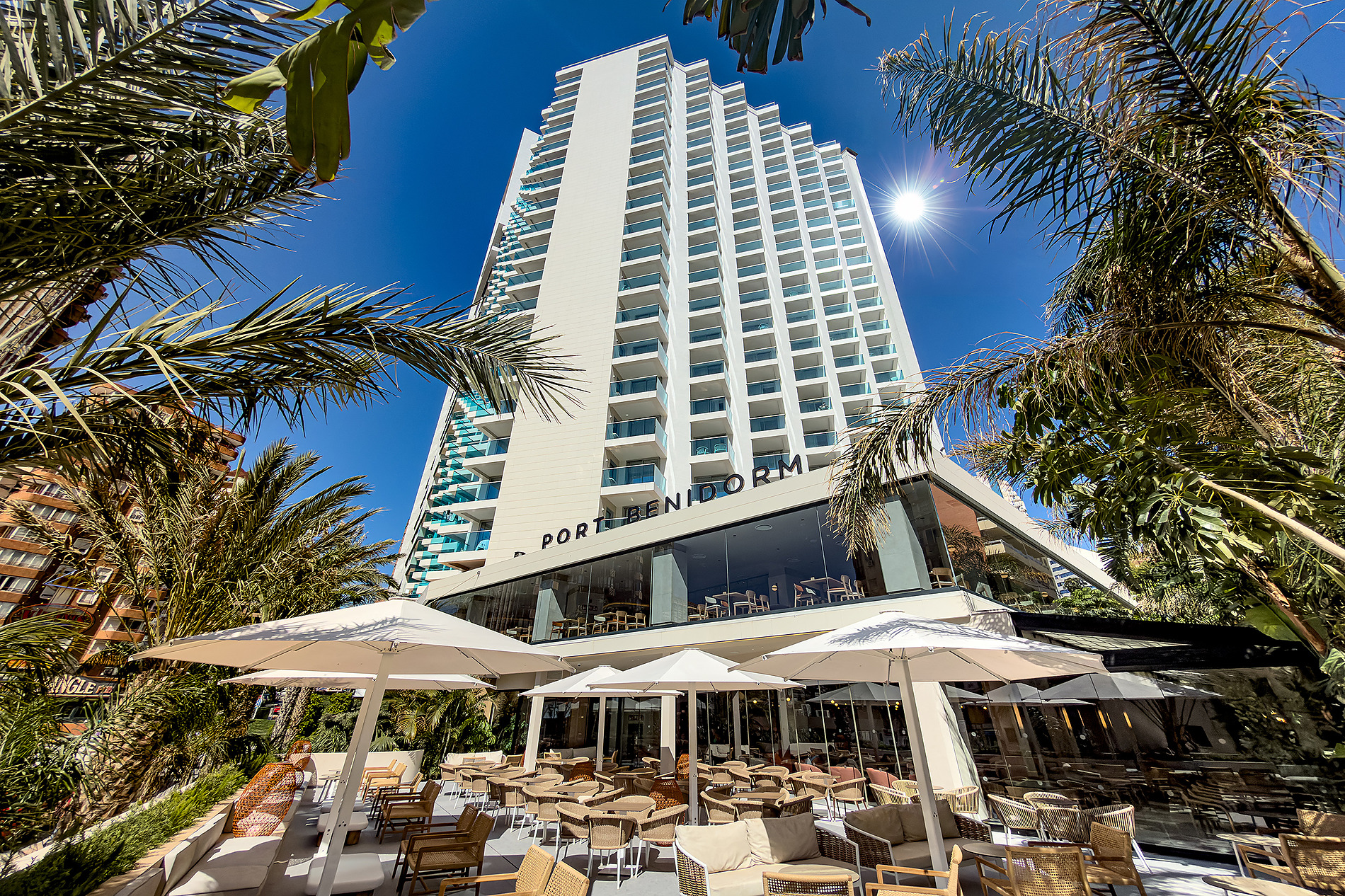 Port Benidorm Hotel & Spa | Alicante | Port Hotels | Web oficial: Hotel Port Benidorm: Fachada con palmeras, terraza y piscina. Foto tomada en un día soleado.