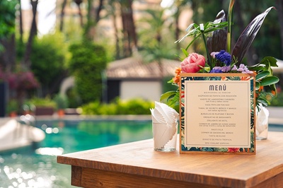 a menu is on a table in front of a pool - 