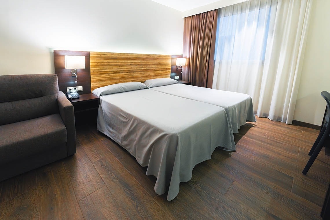 una habitación de hotel con dos camas y una silla