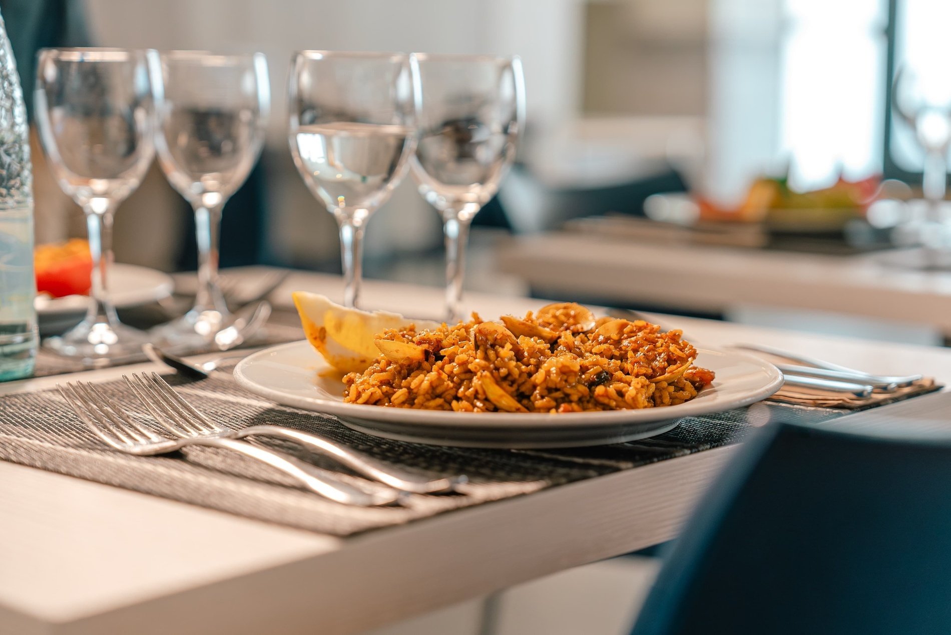 a plate of food sits on a table next to wine glasses