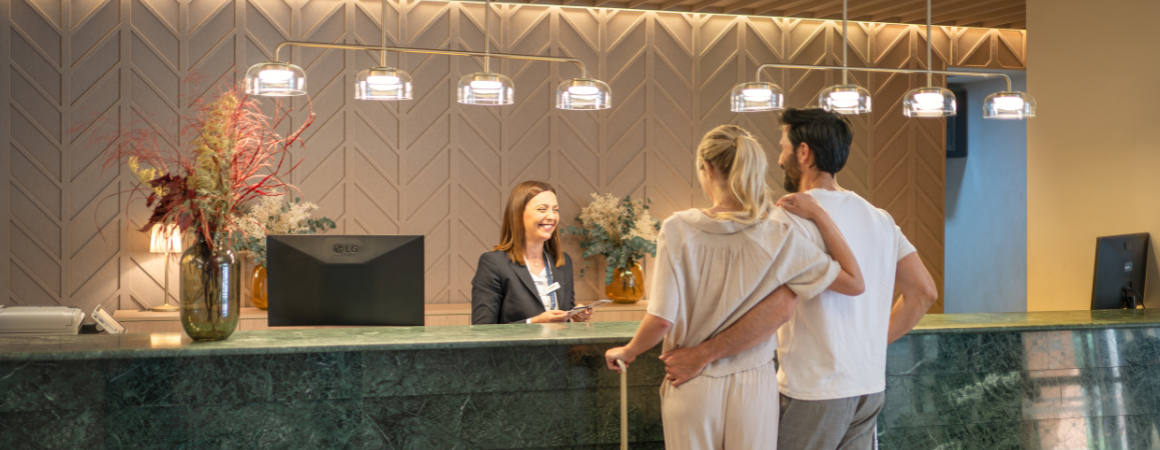 una gran piscina rodeada de palmeras frente a un hotel