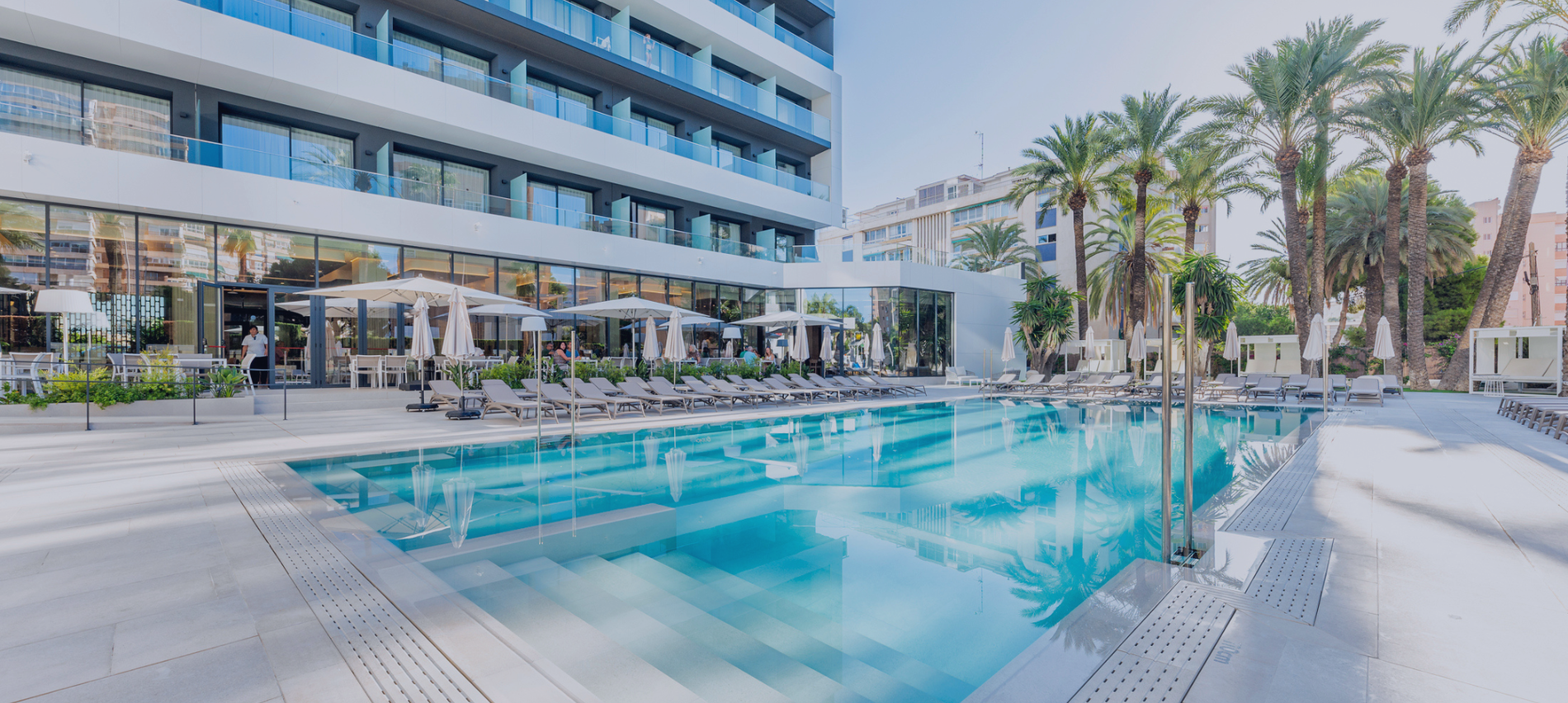 una gran piscina rodeada de sillas y sombrillas en un hotel