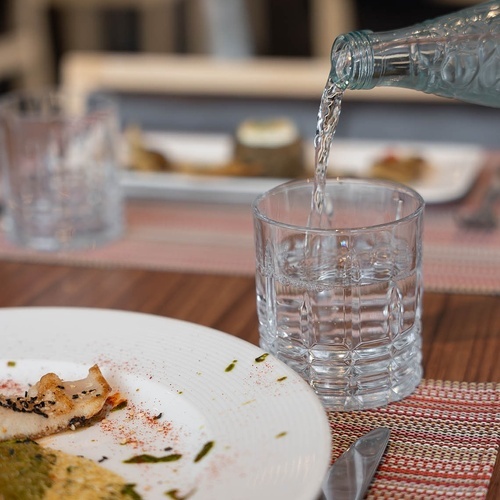 una botella de agua se vierte en un vaso sobre una mesa