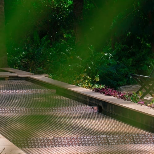 a chair sits near a swimming pool in a garden